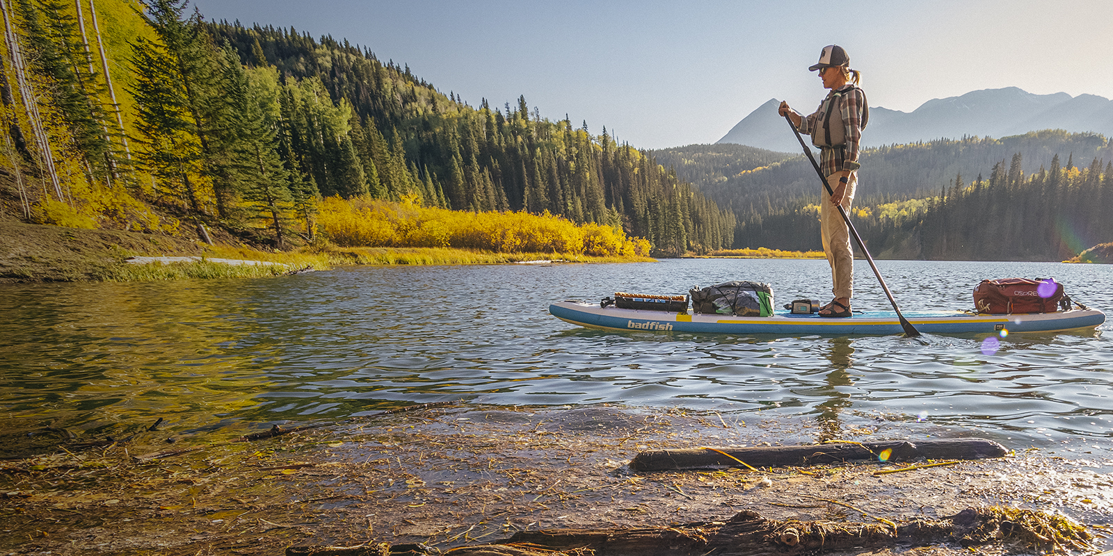 A woman standup paddleboarding in the fall